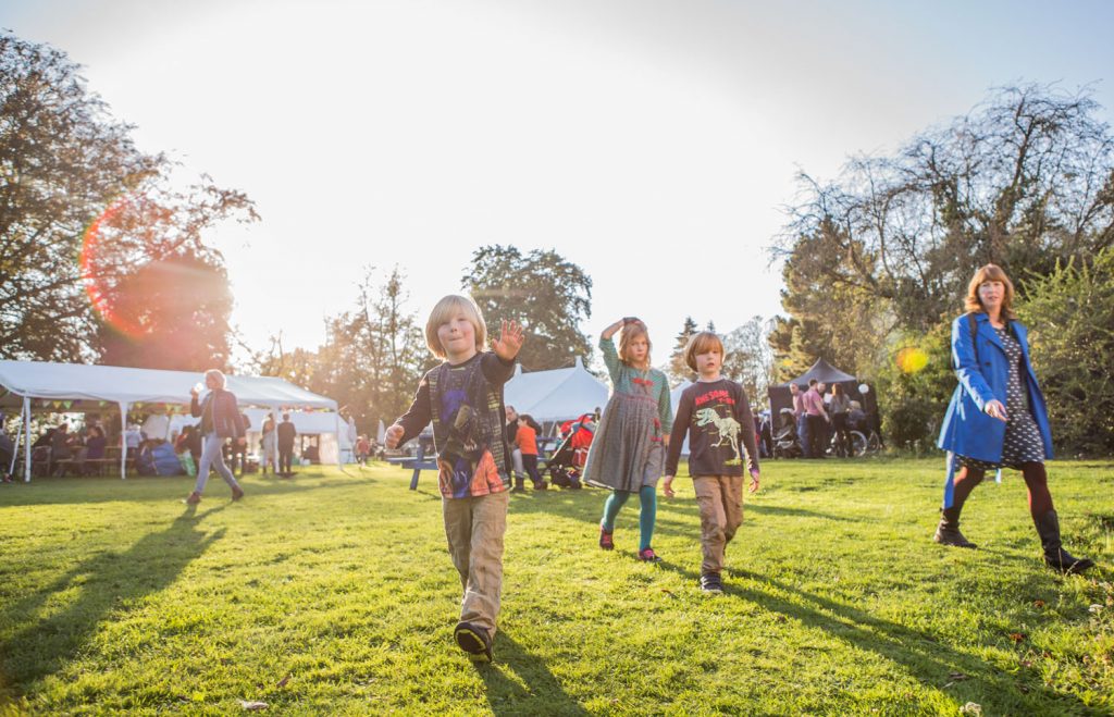 children in field with marquees in background