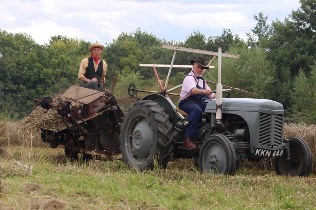 men on old farming tractor and attachment