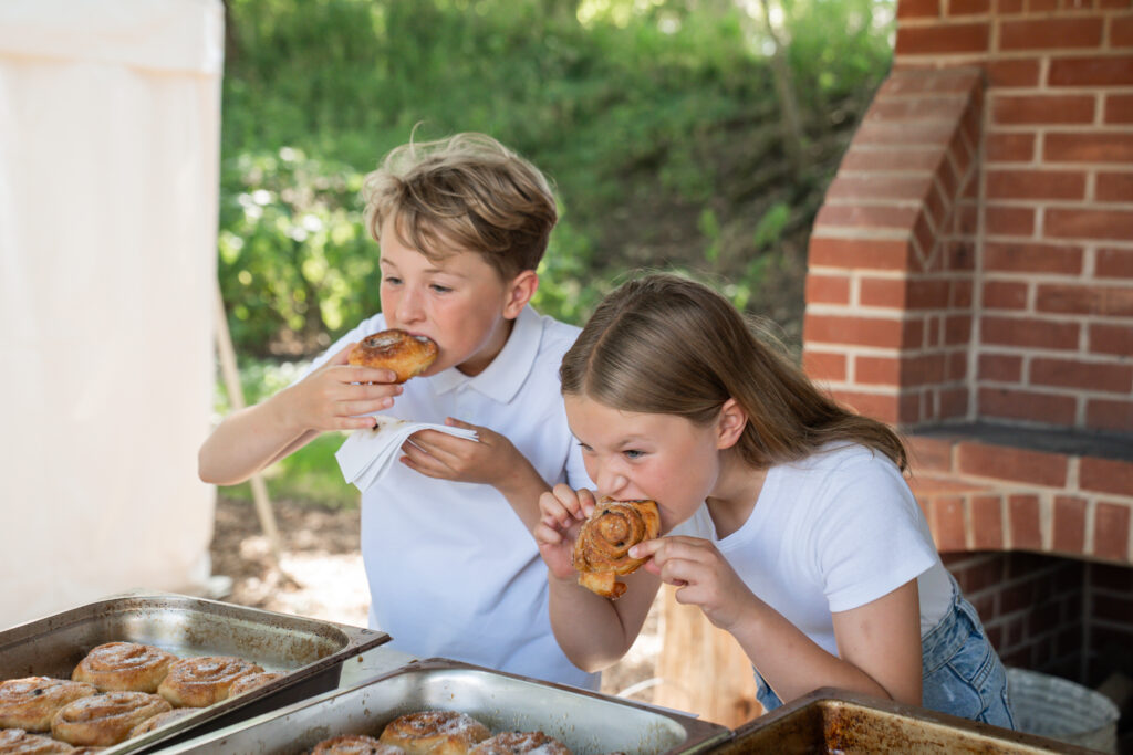 Children eating chelsea buns in the bread oven